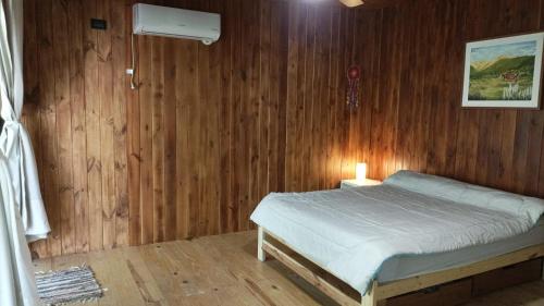 a bedroom with a bed and a wooden wall at Casita en el río, Mayu Sumaj in San Antonio de Arredondo
