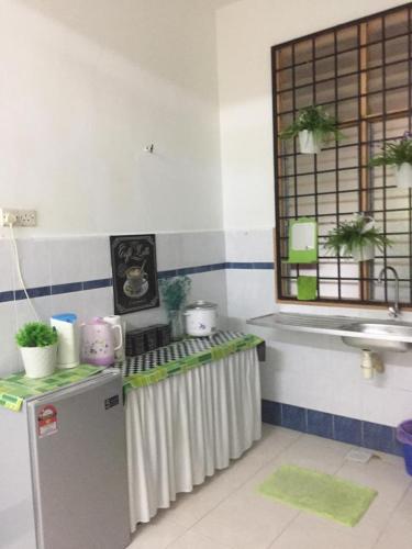 a kitchen with a refrigerator and a counter with a sink at Alai Baker Abodes in Malacca