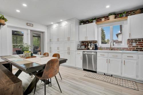 a kitchen with white cabinets and a table with chairs at Saskatoon 5 bedroom-Big Gatherings-Patio-BBQ-Games Room in Saskatoon