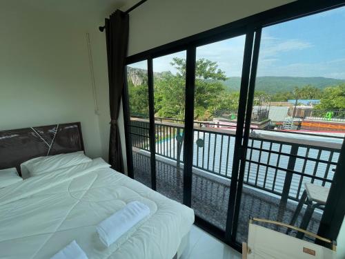 a bedroom with a bed and a balcony with a view at ภูผา เฮ้าส์ รีสอร์ท in Ban Mung