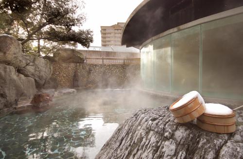a bath tub sitting on the side of a pool of water at Suimeikan in Gero