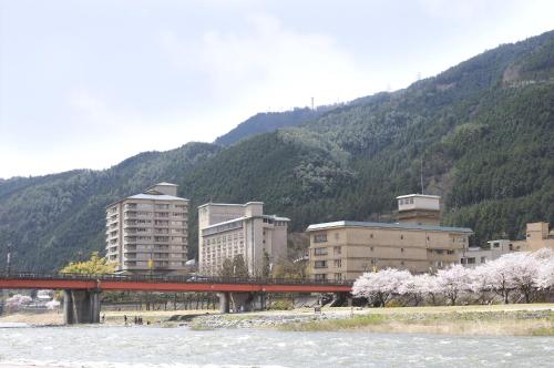 a bridge over a river with buildings and a mountain at Suimeikan in Gero