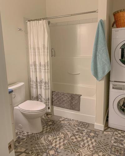 a bathroom with a toilet and a washing machine at Windslow Guest Suite at Kye Bay in Comox