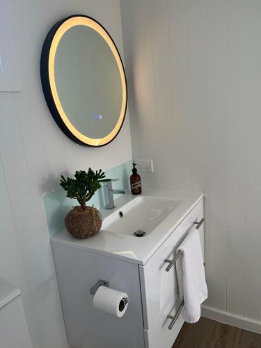 a bathroom with a white sink and a mirror at Matakana Central 981 in Matakana
