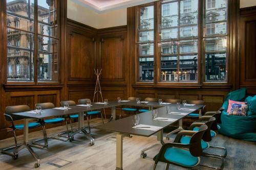 a room with tables and chairs and windows at Aloft Liverpool in Liverpool