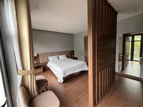 a bedroom with a bed and a room with a chair at Hà Vy Homstay in Móng Cái