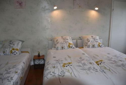 - une chambre avec 2 lits avec des draps blancs et des fleurs dans l'établissement Maison en bord de Rance, à Pleudihen-sur-Rance