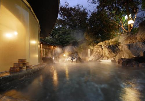 a building with steam coming out of a pool at night at Suimeikan in Gero