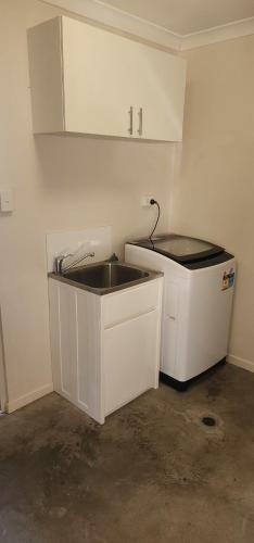 a white kitchen with a sink and a cabinet at Starfish Beach House in Agnes Water