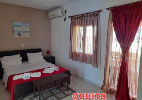 a bedroom with a bed with red sheets and curtains at Delfini in Akhladherí
