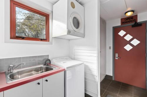 Una pequeña cocina con fregadero y ventana. en Muzzlewood 3, en Thredbo