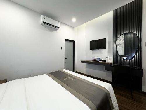 a white bedroom with a bed and a tv at LION 10 HOTEL in Can Tho