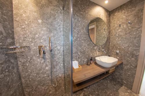 a bathroom with a shower and a sink and a mirror at Kaiser Luxury Suites in Achílleion
