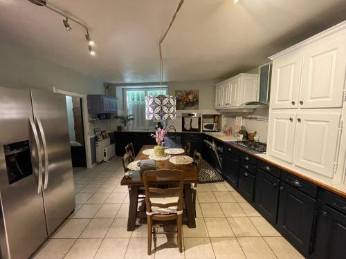 une cuisine avec une table et un réfrigérateur en acier inoxydable dans l'établissement Spacious character house in beautiful Montcuq, à Montcuq