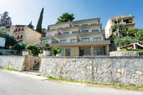 a building behind a stone wall next to a street at Kaiser Luxury Suites in Achílleion
