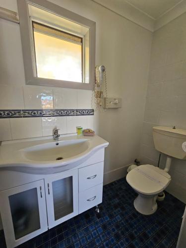 a bathroom with a sink and a toilet and a window at Bellview Motel in Narrabri