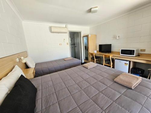 a room with a large bed and a desk at Bellview Motel in Narrabri