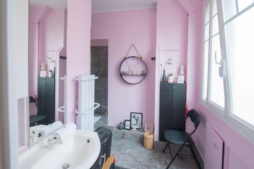 une salle de bains rose avec un lavabo et une chaise dans l'établissement Joséphine Baker , appartement cosy , 2 pièces ensoleillé, à Paris