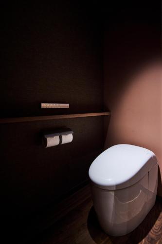 a bathroom with a white toilet in a black room at ITSUKUSHIMA IROHA in Miyajima