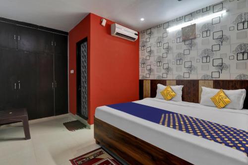 SPOT ON Hotel C S Tower في لاكناو: غرفة نوم بسرير وجدار احمر