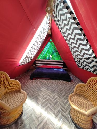 uma tenda vermelha com 2 cadeiras e uma janela em TravelOn Manali Resort em Manali