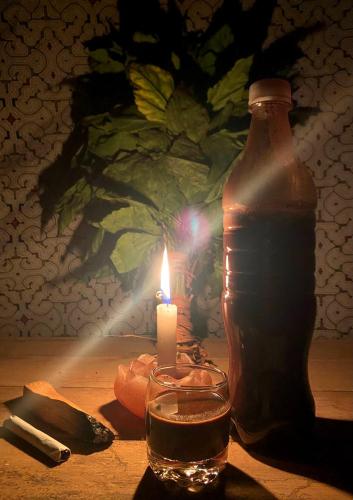 a candle and a bottle on a table with a glass at Hostel AYA-NI in Pucallpa