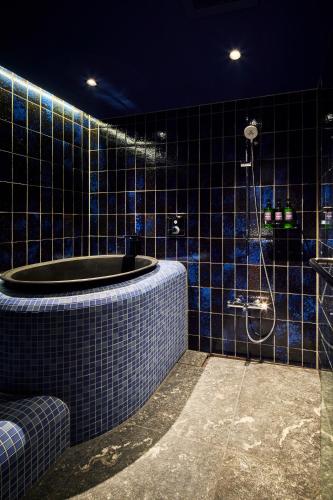 a blue tiled bathroom with a tub and a shower at ITSUKUSHIMA IROHA in Miyajima