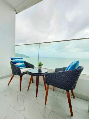 two chairs and a table on a balcony with the ocean at Căn hộ TMS Quy Nhơn KIM NGÂN in Quy Nhon