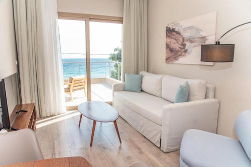 a living room with a white couch and a view of the ocean at Kaiser Luxury Suites in Achílleion