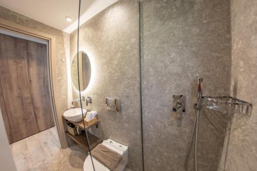a bathroom with a shower and a toilet and a sink at Kaiser Luxury Suites in Achílleion