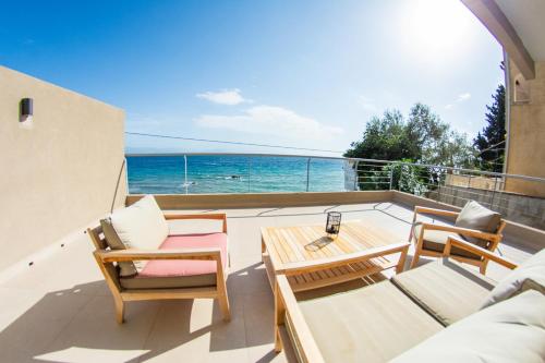 a balcony with chairs and a table and the ocean at Kaiser Luxury Suites in Achílleion