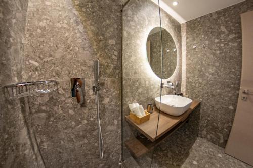 a bathroom with a shower and a sink and a mirror at Kaiser Luxury Suites in Achílleion