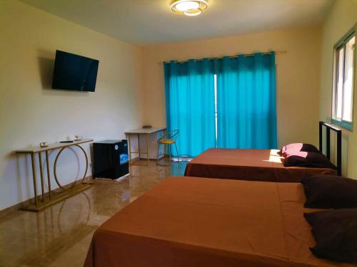 a hotel room with two beds and a television at Hôtel La Kapila Ivato in Ivato