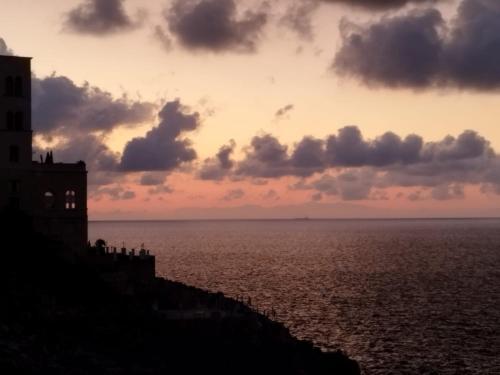 a sunset over the ocean with a lighthouse at Casa Archi Santa Cesarea Terme in Santa Cesarea Terme