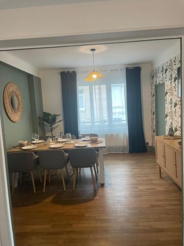 - une salle à manger avec une table, des chaises et des rideaux bleus dans l'établissement Appartement calais nord, à Calais