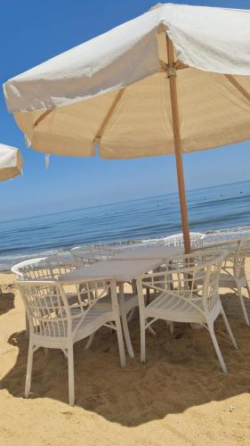a table and chairs under an umbrella on the beach at شالية غرفتين وصاله ارضي عمارة 10 in `Ezbet Shalabi el-Rûdi