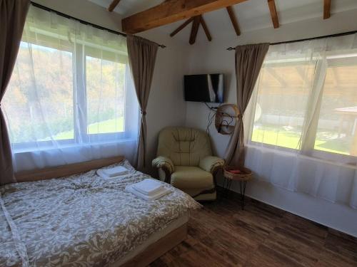 Un dormitorio con una cama y una silla y ventanas. en Vila agapi -Вила Любов, en Elhovo