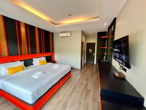 a bedroom with a large bed and a flat screen tv at WOW PHUKET in Phuket Town