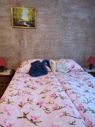 a bed with a pink blanket with flowers on it at Zeleni raj in Hreljin Ogulinski