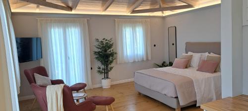 1 Schlafzimmer mit einem Bett, einem TV und 2 Stühlen in der Unterkunft Verani suites Lefkas Town in Lefkada Town