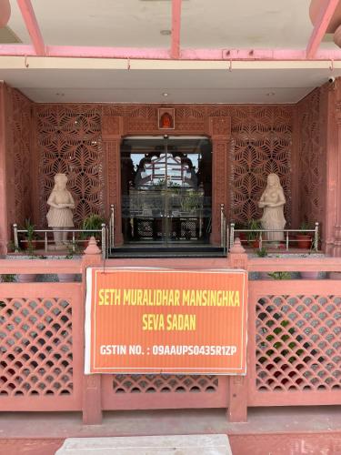 a sign in front of a building with two statues at Hotel Seth Murlidhar Seva Sadan-Near Prem Mandir in Vrindāvan