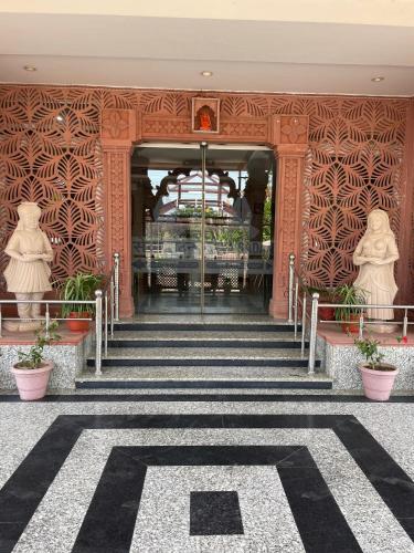 a staircase leading to a building with two statues at Hotel Seth Murlidhar Seva Sadan-Near Prem Mandir in Vrindāvan