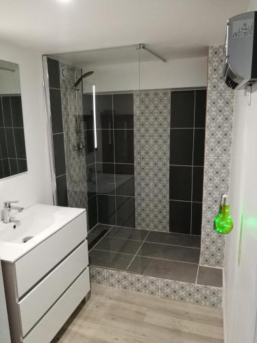 La salle de bains est pourvue d'une douche et d'un lavabo blanc. dans l'établissement Maison Climatisée avec Spa d'avril à fin septembre, à Royan
