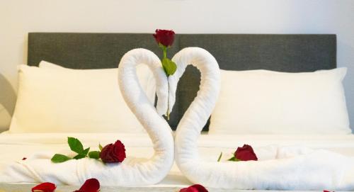 two swans sitting on a bed with roses at MOONWAY SUITES At EATON KLCC in Kuala Lumpur