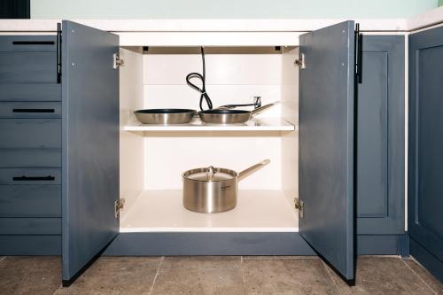 a kitchen with blue cabinets and a pot on a shelf at Full Moon Apartments & Villa - Hoi An in Hoi An