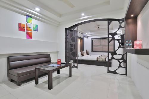 a room with a bed and a couch and a table at Hotel Nova Cross Road in Rajkot