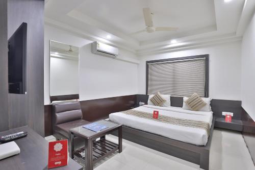 a small bedroom with a bed and a tv at Hotel Nova Cross Road in Rajkot