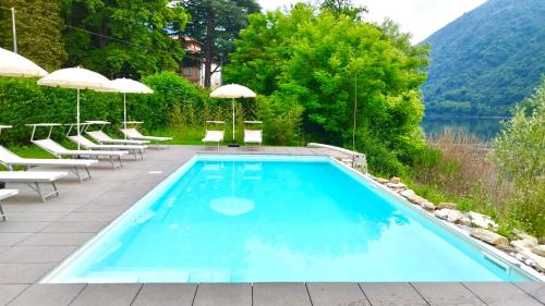 a pool with chairs and umbrellas next to a lake at La Villa del Lago in Ghirla