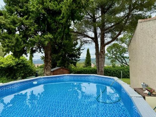 une piscine bleue dans une cour arborée dans l'établissement Maison de Mireille et Bernard, au Beausset