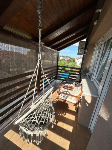 a porch with a swing and chairs on a balcony at Apartman Gaby in Virovitica